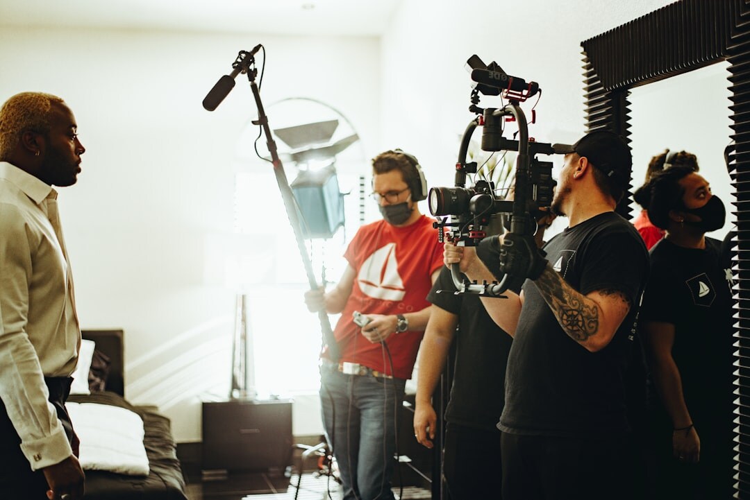 Small documentary film crew setting up camera and lighting equipment indoors